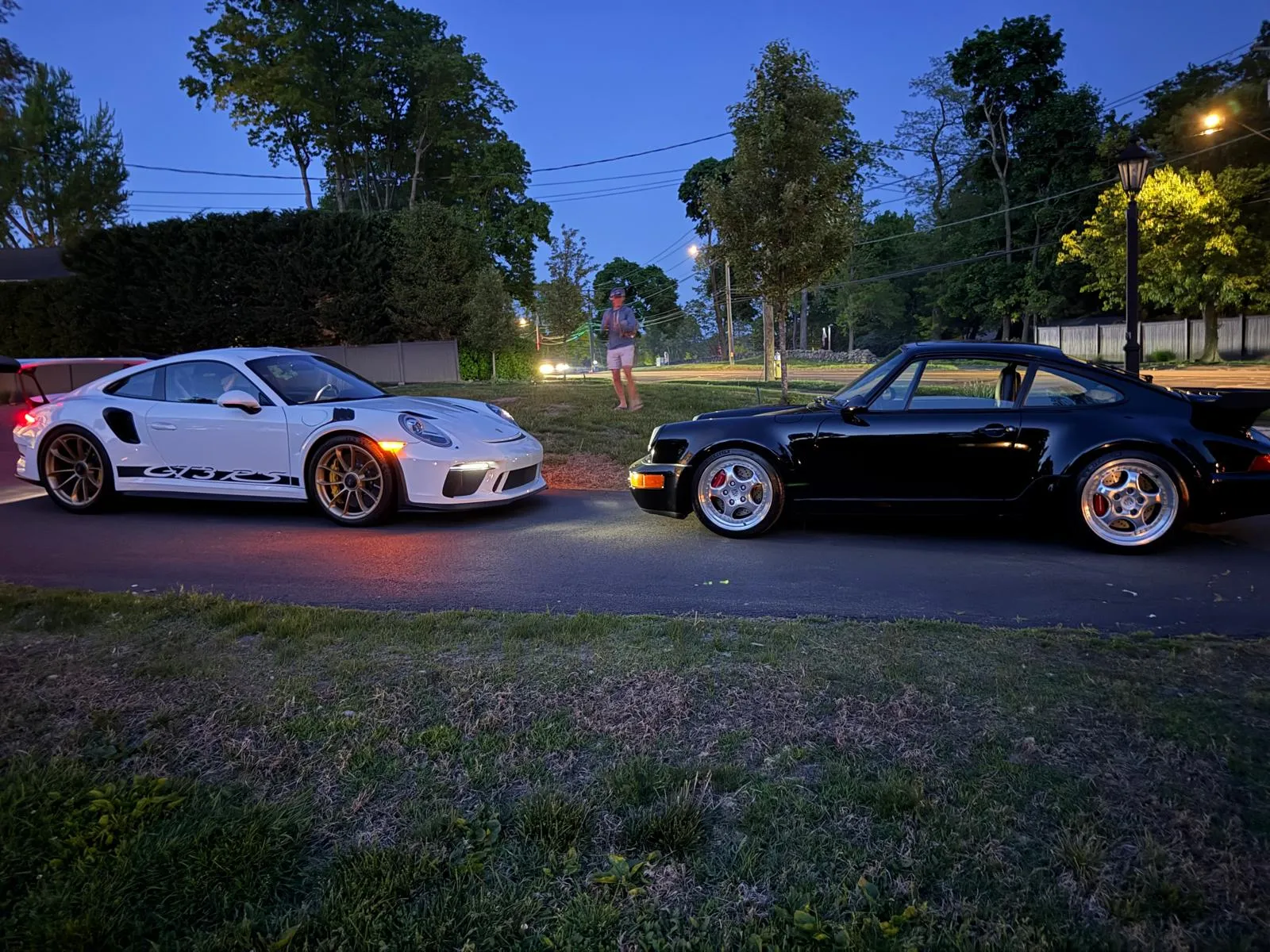 White Porsche GT3 RS and classic black Porsche parked nose to nose at dusk