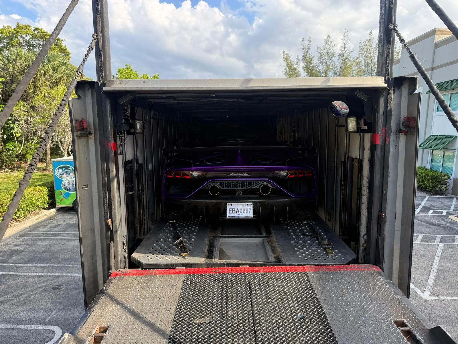 Purple Lamborghini secured inside enclosed trailer on liftgate